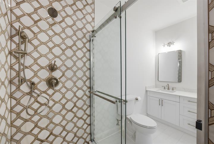 Bath with patterned tile shower and frameless glass