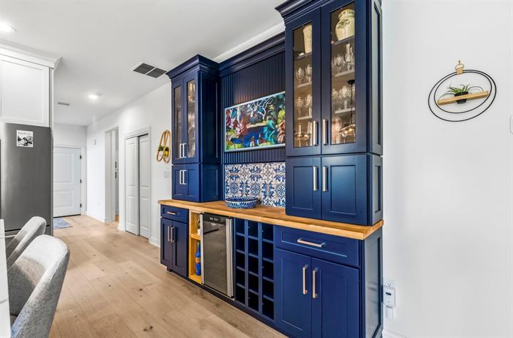 Built-in bar: Navy cabinetry with glass-front uppers, wine refrigerator and wine rack