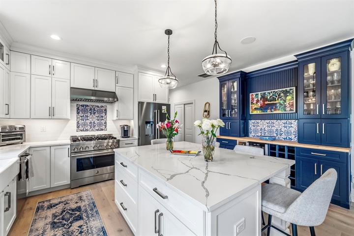 Chef's kitchen: Marble-look quartz island, pendant lighting and a navy built-in