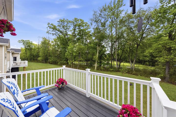 Rear deck with Adirondack chairs looking out over lawn and trees