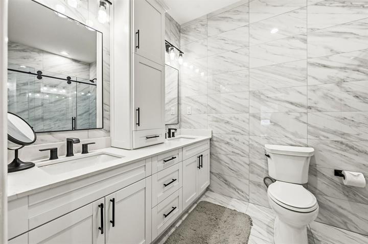 Owner's bath with marble-look tile and a double vanity